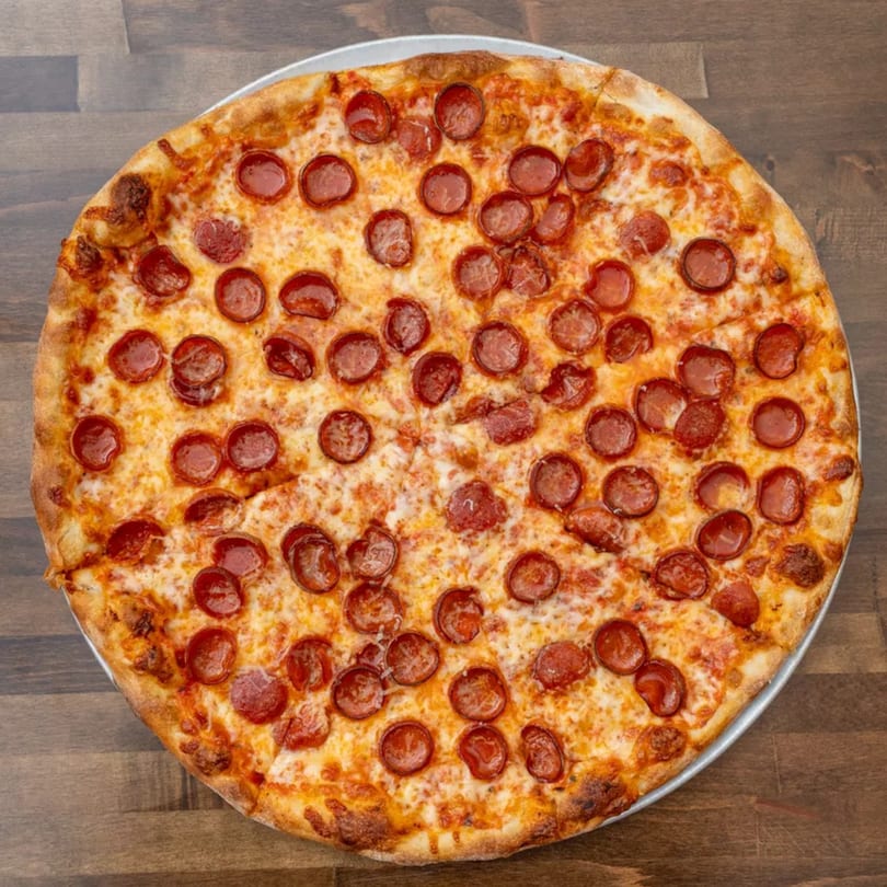 A whole pepperoni pizza with melted cheese and a golden crust on a wooden table.