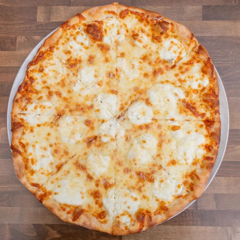 A whole white pizza with melted mozzarella and dollops of ricotta cheese, sliced into eight pieces.